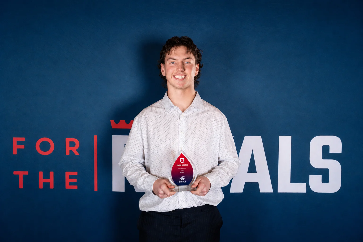 Simon Bourne holding the Redeemer Royals men's volleyball team MVP award.